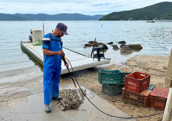 Brazil: Worker cleans fouled cultivation lines with high-pressure water to extend their usability.